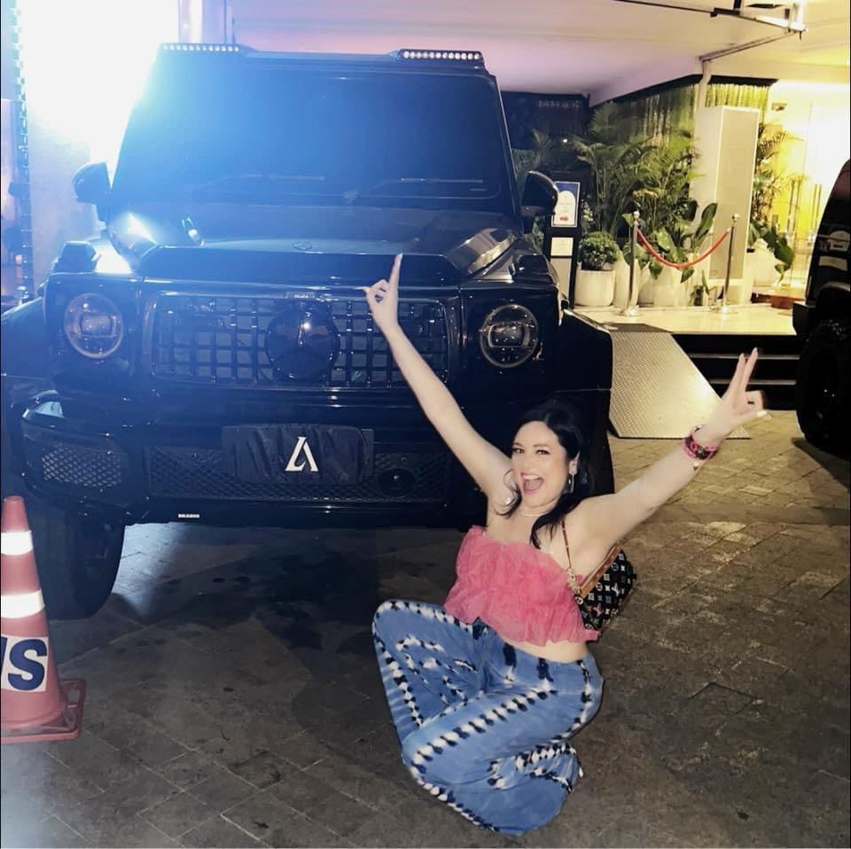 A woman sitting on the ground in front of a jeep.