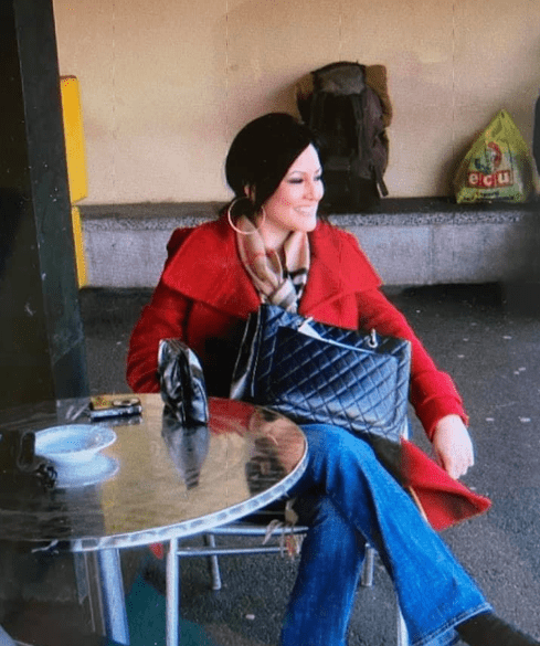 A woman sitting at an outdoor table with her purse.