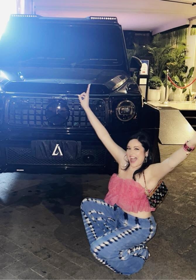 A woman sitting on the ground in front of a jeep.